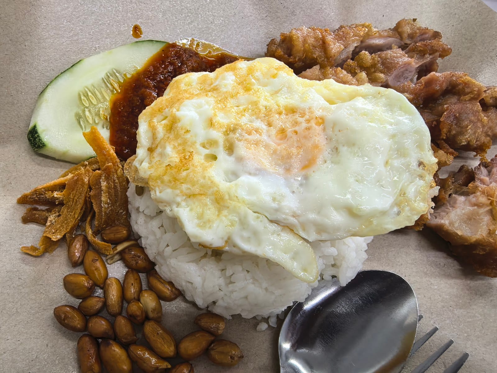 Nasi lemak with fried chicken, fried egg, sambal, cucumber, peanuts and fried anchovies